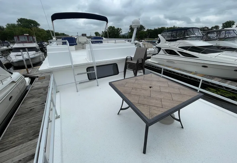 Slide: The Image of 2003 Gibson 50 Classic houseboat with outdoor seating and table on deck, docked at marina. - 12