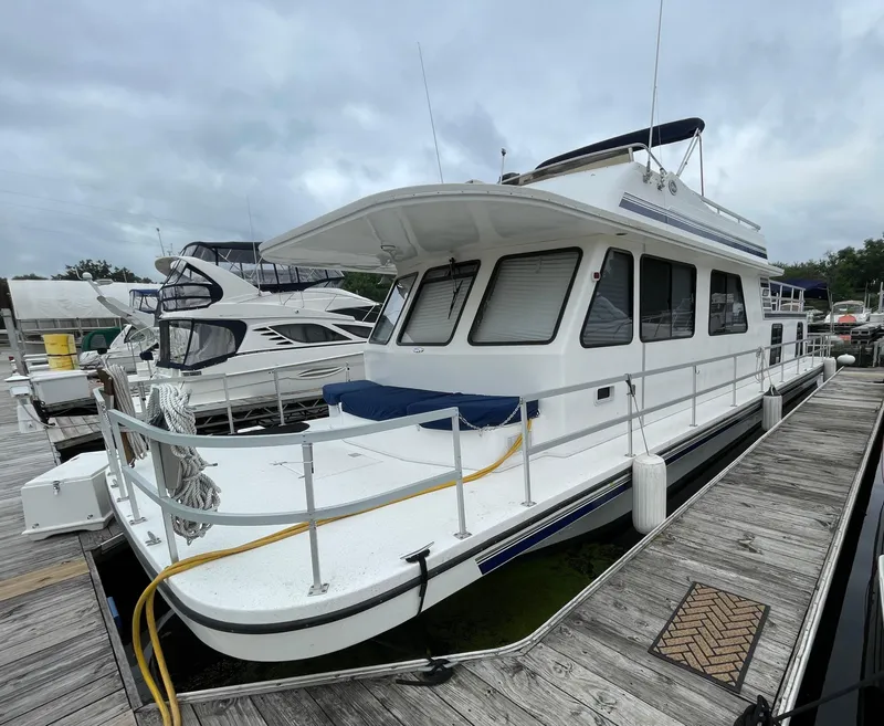 Slide: The Image of A 2003 Gibson 50 Classic houseboat docked at a marina under cloudy skies. - 3