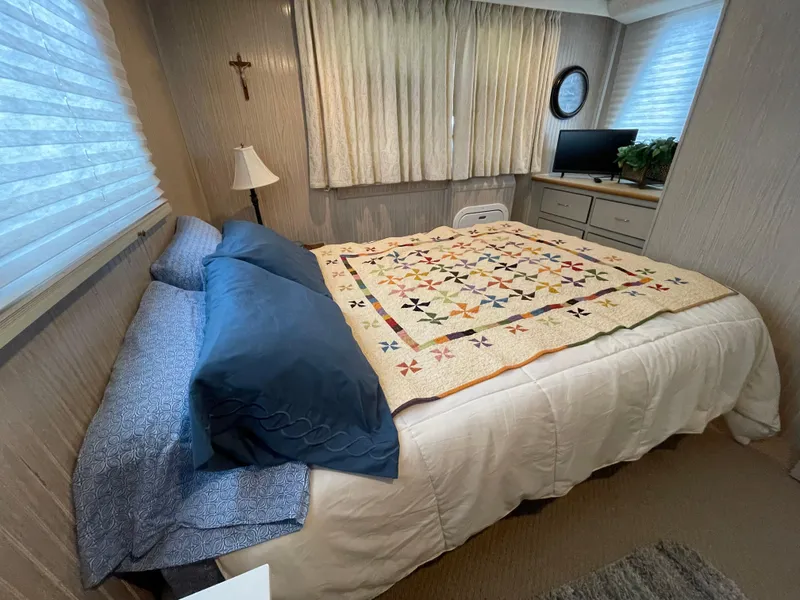Slide: The Image of Cozy bedroom with quilted bedspread, blue pillows, and a small TV on a dresser. - 32