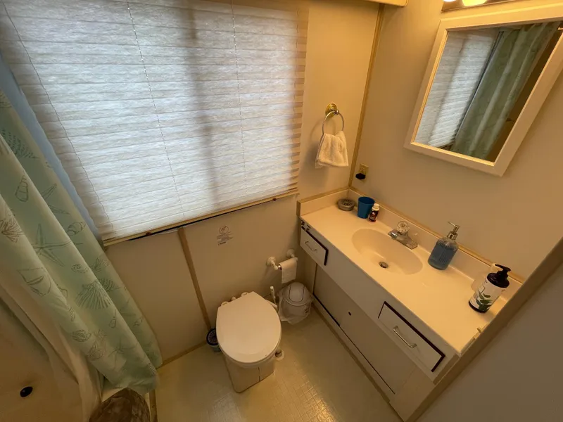 Slide: The Image of A compact bathroom with a toilet, sink, and mirror, featuring a shower curtain and window blinds. - 35