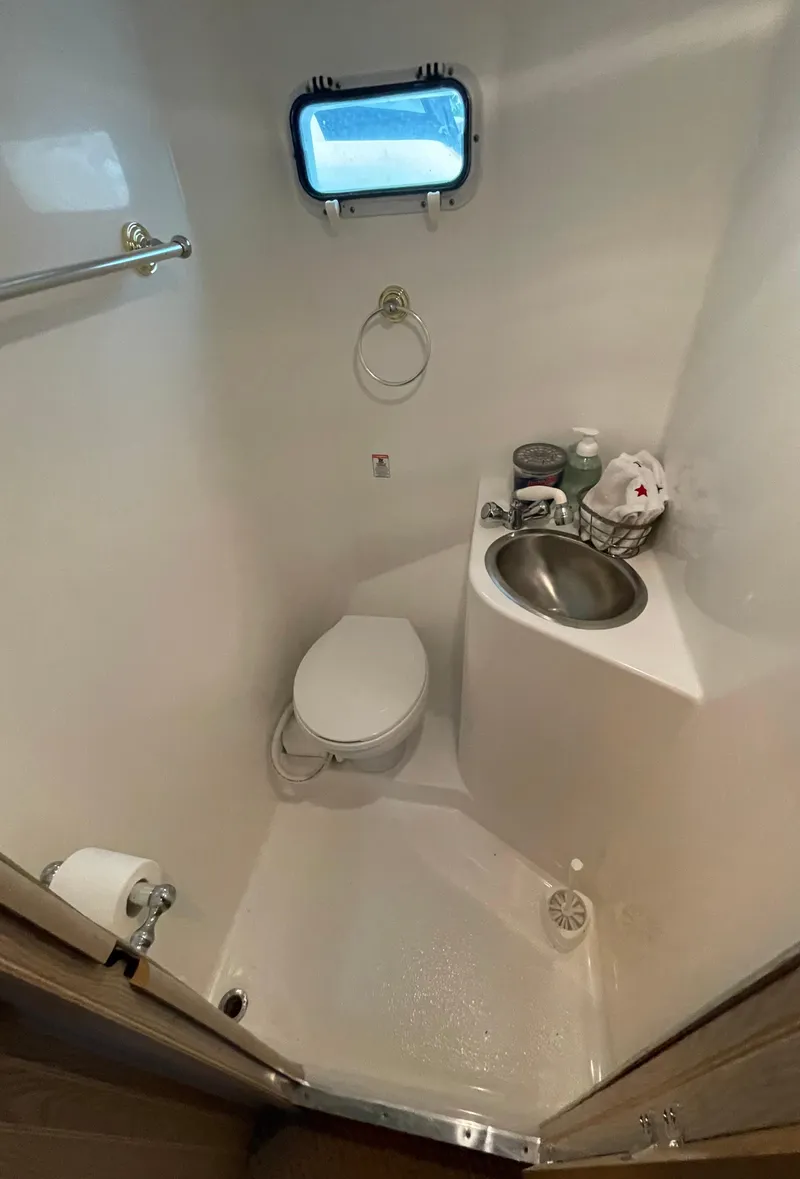 Slide: The Image of Compact bathroom in a 2003 Gibson 50 Classic boat with toilet, sink, and porthole. - 40