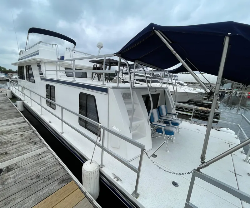 Slide: The Image of 2003 Gibson 50 Classic houseboat docked, featuring spacious deck and seating under a canopy. - 6