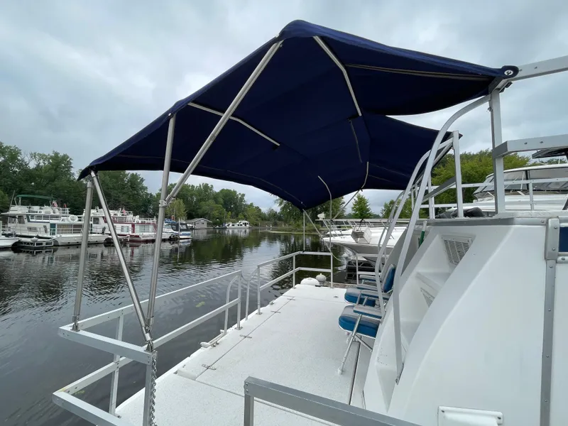 Slide: The Image of 2003 Gibson 50 Classic boat with blue canopy on a calm river. - 7