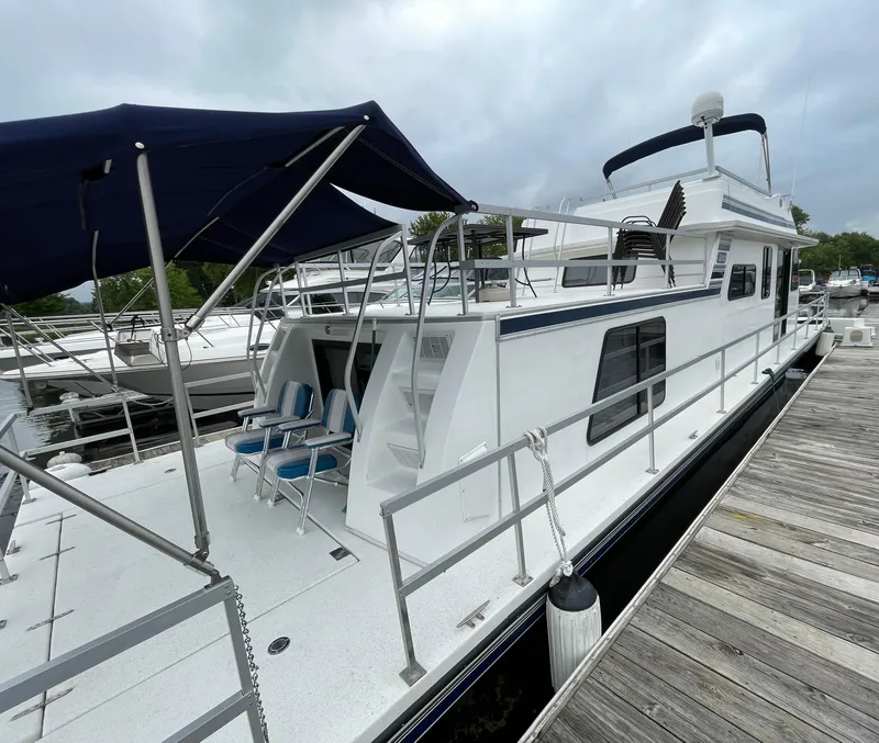 Slide: The Image of 2003 Gibson 50 Classic houseboat docked with blue canopy and outdoor seating. - 8