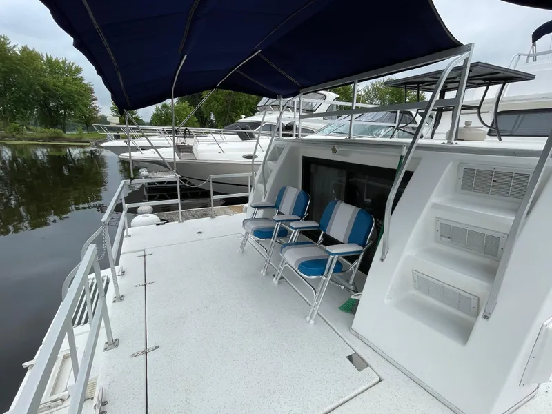 Slide: The Image of 2003 Gibson 50 Classic yacht deck with blue chairs and canopy, docked by water. - 9