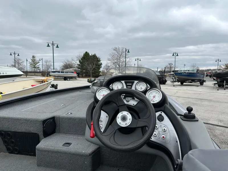 Slide: The Image of 2017 Tracker Pro Team 195 TXW boat dashboard with steering wheel and gauges, parked outdoors. - 2