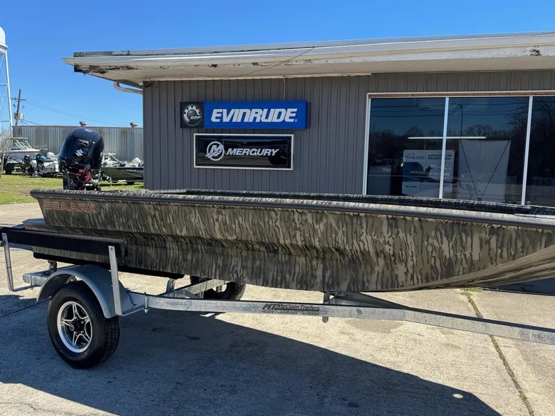 The Image of 2025 SeaArk 1648 Slayer Pro boat on trailer outside dealership with Evinrude and Mercury signs. - 1