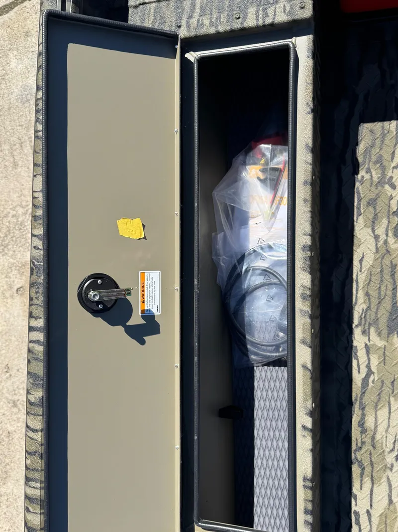 Slide: The Image of Open storage compartment in 2025 SeaArk 1648 Slayer Pro boat, showing interior contents. - 16