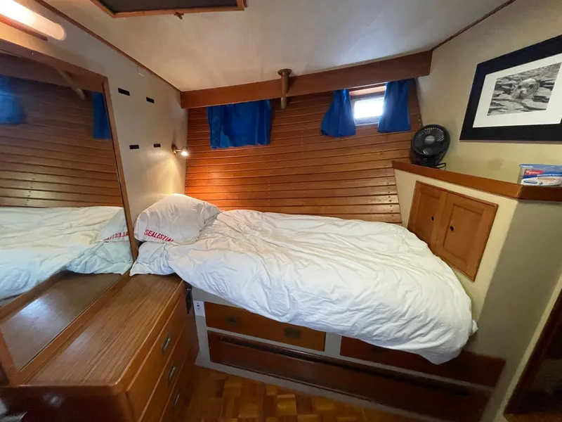 Slide: The Image of Cozy cabin bedroom in 1972 Grand Banks Alaskan 55 yacht with wooden accents and blue curtains. - 29