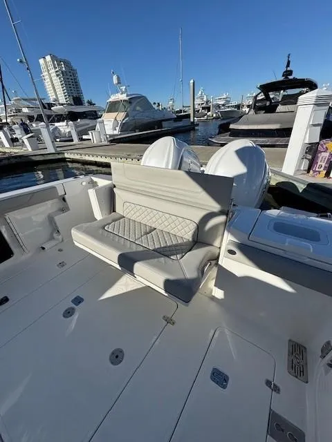 Slide: The Image of 2025 Pursuit S 328 Sport boat interior at marina, featuring cushioned seating and twin engines. - 8