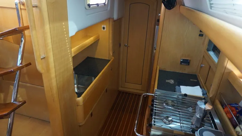 Slide: The Image of Interior of 2008 Oyster 46 yacht, featuring wooden cabinetry and compact kitchen area. - 37