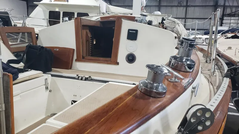 Slide: The Image of 1981 Shannon 28 sailboat interior with wooden trim and winches in a marina setting. - 10