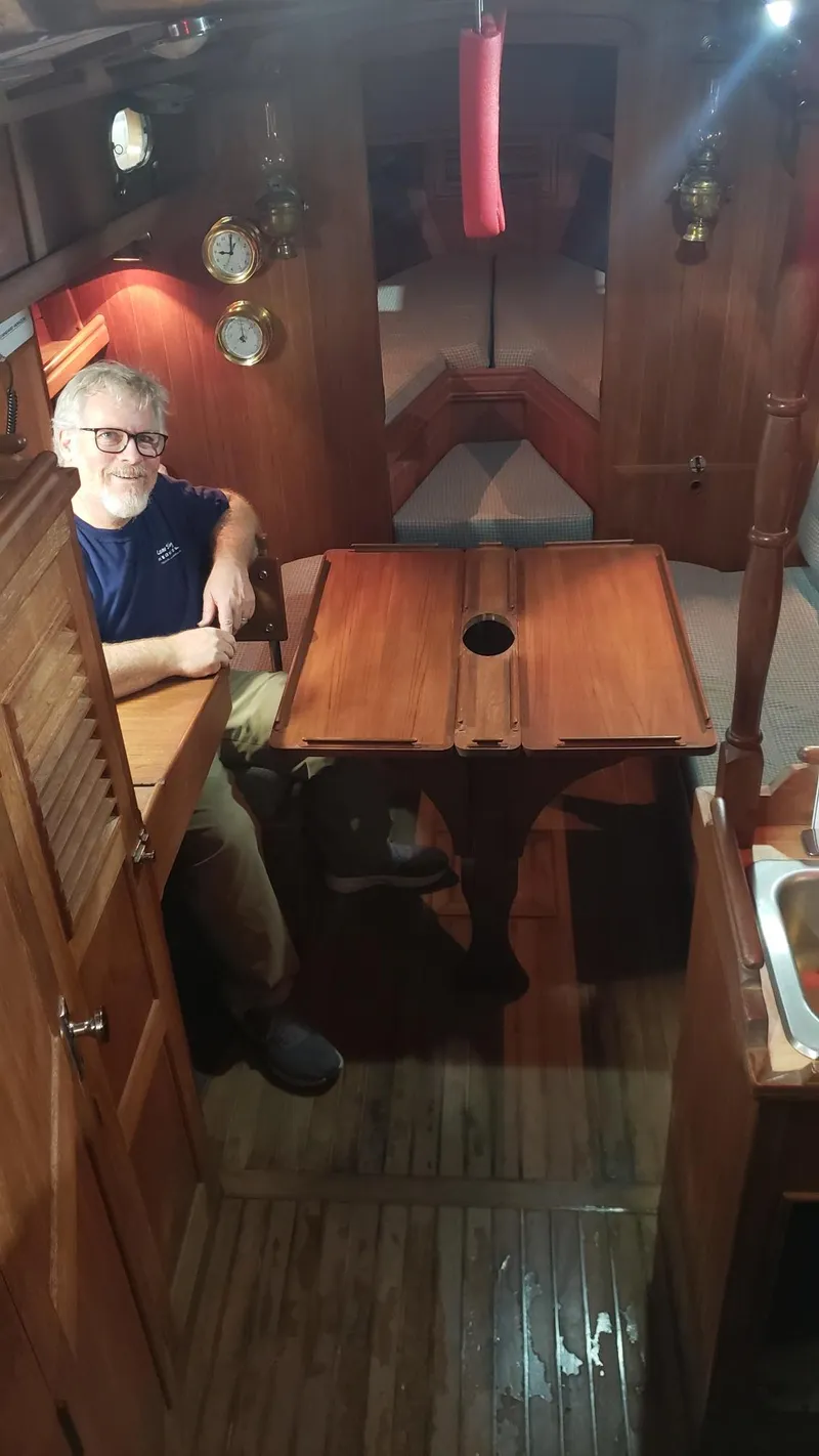Slide: The Image of Interior of a 1981 Shannon 28 sailboat with wooden furnishings and a person seated at a table. - 16