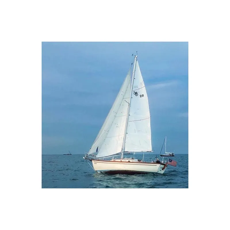 Slide: The Image of 1981 Shannon 28 sailboat on calm ocean with American flag, under clear blue sky. - 4