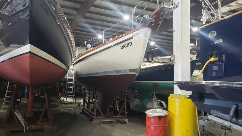 Slide: The Image of 1981 Shannon 28 sailboat named "Druid" in a boatyard, surrounded by other vessels. - 6