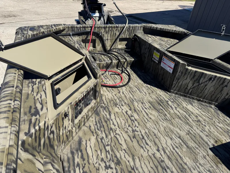 Slide: The Image of 2025 SeaArk Mud Runner 180 boat interior with camo design and open storage compartments. - 12
