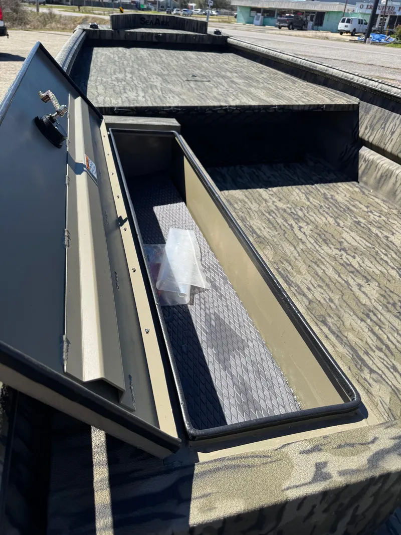 Slide: The Image of 2025 SeaArk Mud Runner 180 boat with open storage compartment, camo design. - 13