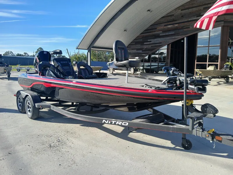 Slide: The Image of 2024 Nitro Z20 boat on trailer, sleek design, red and black accents, parked outdoors. - 8
