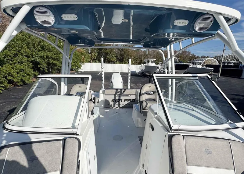 Slide: The Image of 2023 Sea Pro 240 DC boat interior with seating and canopy, parked outdoors. - 18