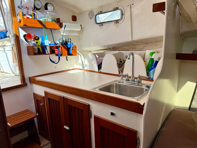Slide: The Image of 1978 Dyer 29 Trunk Cabin interior with sink, wooden cabinets, and nautical equipment. - 19
