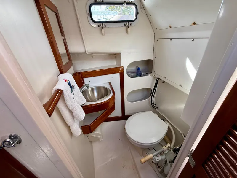 Slide: The Image of 1978 Dyer 29 Trunk Cabin bathroom with sink, toilet, and porthole window. - 21