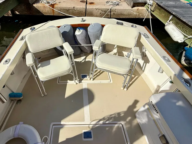 Slide: The Image of 1978 Dyer 29 Trunk Cabin boat interior with two white chairs and docked setting. - 22