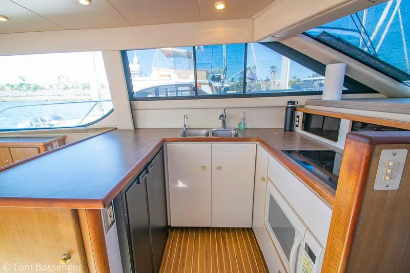 Slide: The Image of 2001 Bayliner 3788 Command Bridge Motoryacht kitchen with wood accents and large windows. - 13