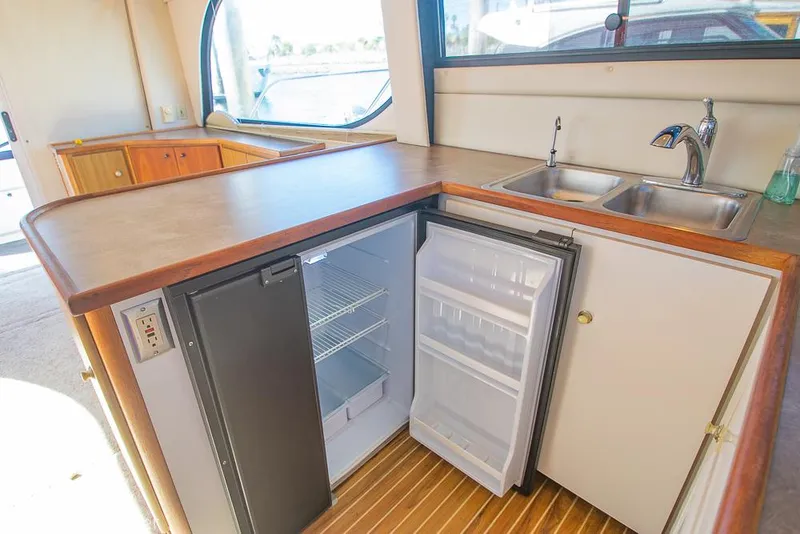 Slide: The Image of 2001 Bayliner 3788 yacht kitchen with open fridge, sink, and wooden flooring. - 16