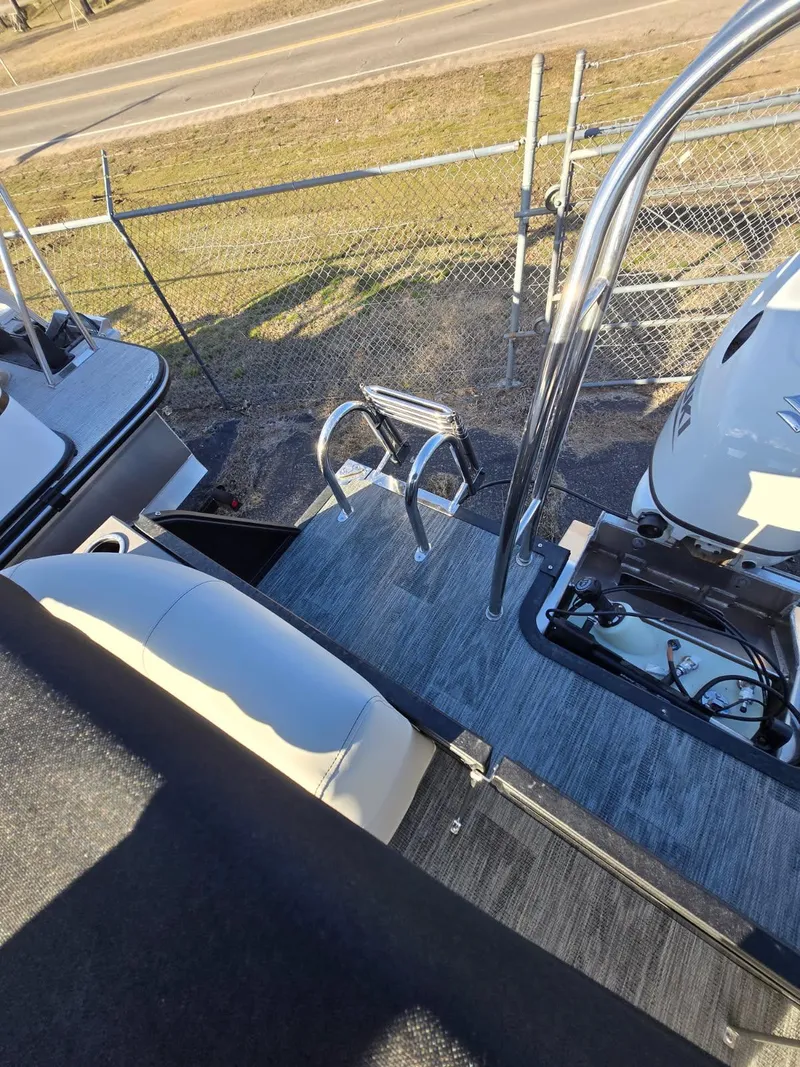 Slide: The Image of 2025 Quest L Class 20RLS boat deck with ladder and railing, parked near a fence. - 10