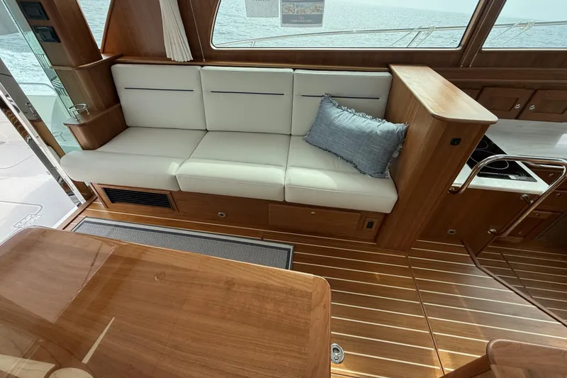 Slide: The Image of 2025 Sabre 45 Salon Express interior with white seating, wooden flooring, and ocean view. - 14