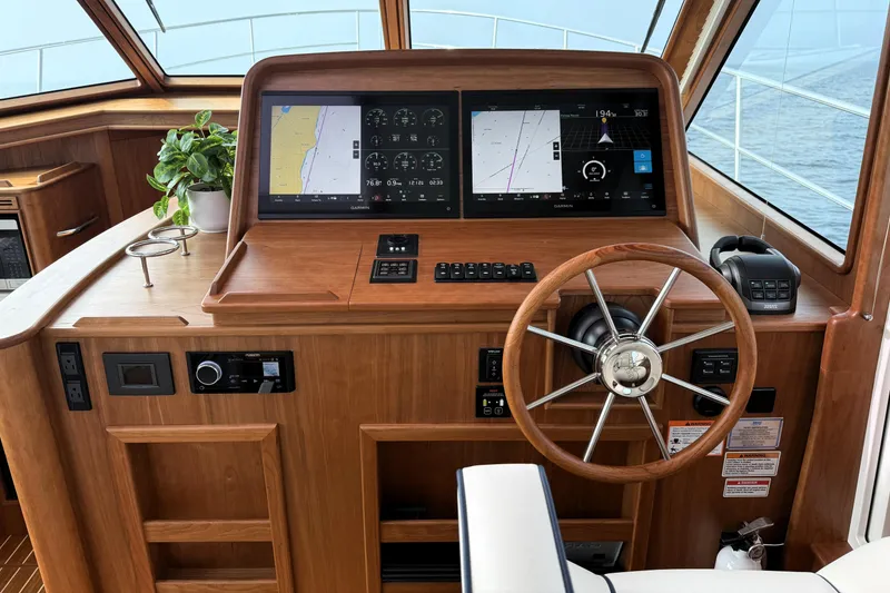 Slide: The Image of Helm of 2025 Sabre 45 Salon Express with dual navigation screens and wooden steering wheel. - 19