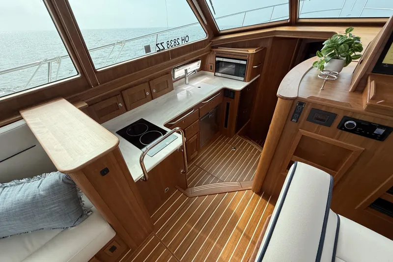 Slide: The Image of 2025 Sabre 45 Salon Express interior with wooden cabinetry and modern kitchen appliances. - 20