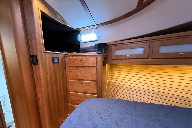 Slide: The Image of 2025 Sabre 45 Salon Express interior with wood cabinetry, TV, and ambient lighting. - 26