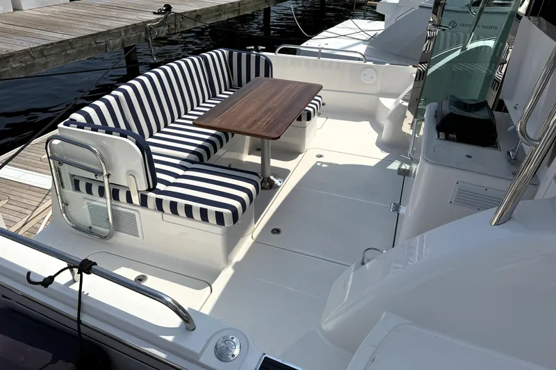 Slide: The Image of 2025 Sabre 45 Salon Express yacht with striped seating and wooden table on deck. - 6