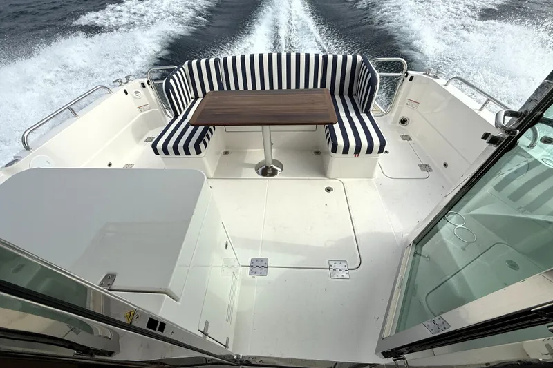 Slide: The Image of 2025 Sabre 45 Salon Express yacht with striped seating and wooden table on deck. - 8