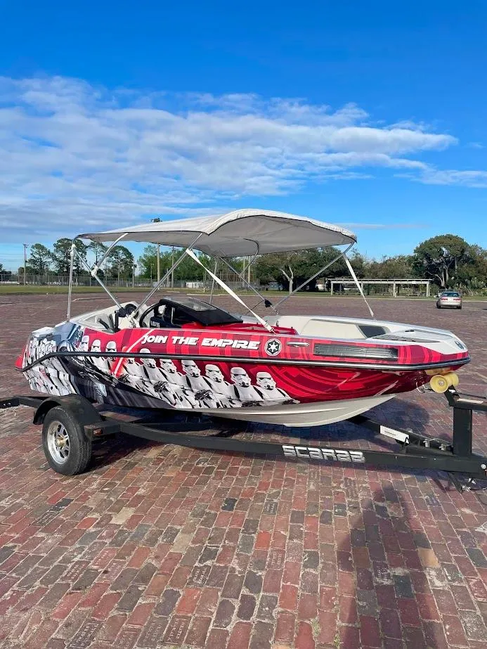 Slide: The Image of 2017 Scarab 165 HO boat with custom graphics on a trailer, parked outdoors. - 1