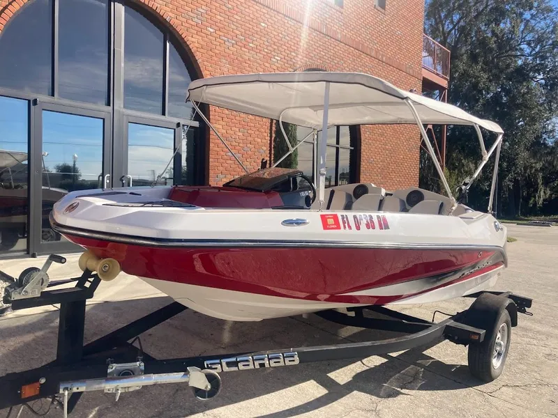 Slide: The Image of 2017 Scarab 165 HO boat with canopy on trailer, parked near brick building. - 19