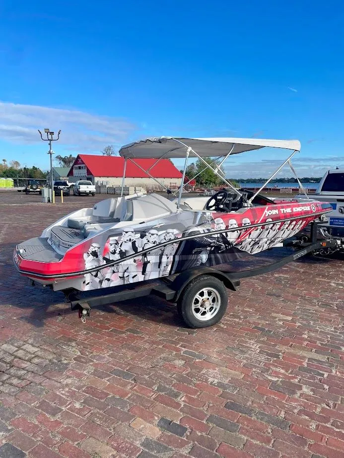 Slide: The Image of 2017 Scarab 165 HO boat with vibrant graphics, parked on a brick surface under a clear sky. - 2