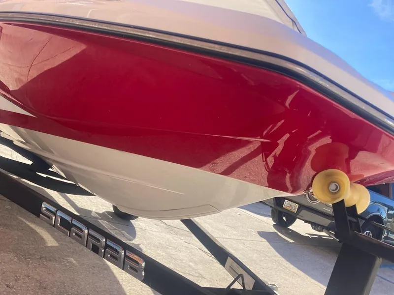 Slide: The Image of 2017 Scarab 165 HO boat on trailer, red and white hull, sunny day. - 24