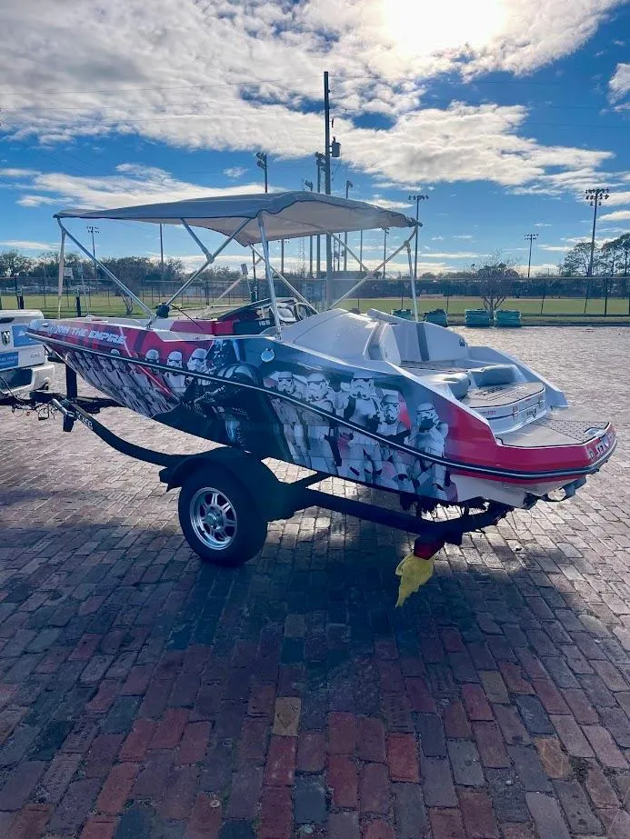 Slide: The Image of 2017 Scarab 165 HO boat with custom graphics on a trailer, parked on brick pavement. - 4