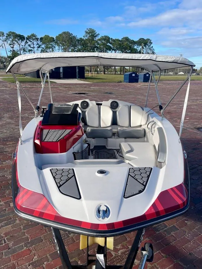 Slide: The Image of 2017 Scarab 165 HO boat with canopy on brick pavement, surrounded by trees. - 6