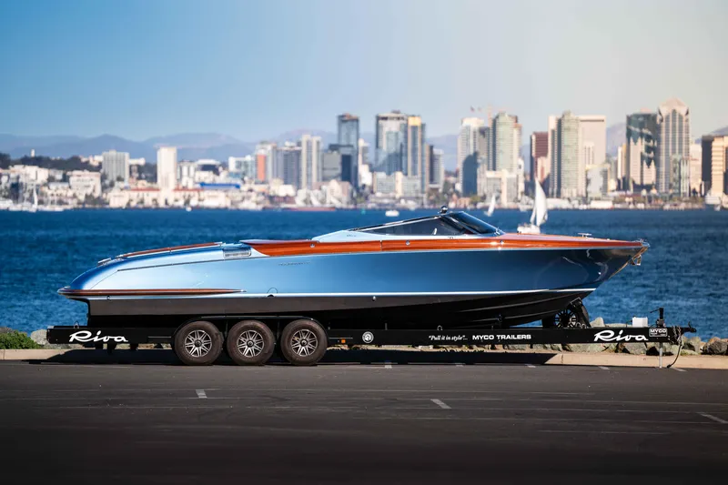 Slide: The Image of 2025 Riva Aquariva 33 boat on trailer with city skyline in background. - 13