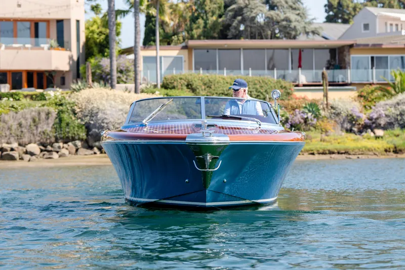 Slide: The Image of 2025 Riva Aquariva 33 luxury boat cruising near waterfront homes. - 2