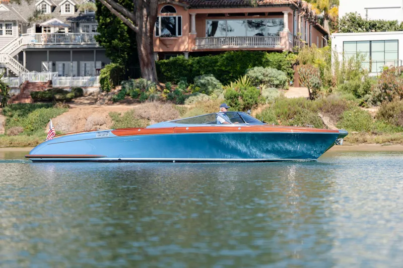Slide: The Image of 2025 Riva Aquariva 33 cruising on a serene waterway, with elegant waterfront homes in the background. - 3
