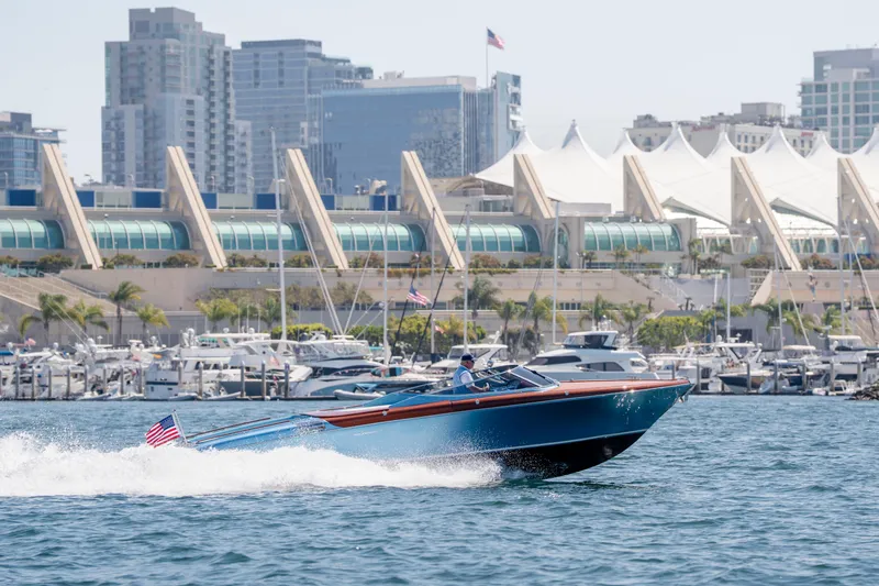 Slide: The Image of 2025 Riva Aquariva 33 cruising in a marina with cityscape backdrop. - 6