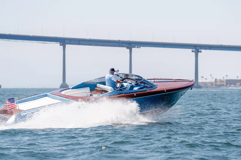 Slide: The Image of 2025 Riva Aquariva 33 cruising on water near a bridge, American flag visible. - 8