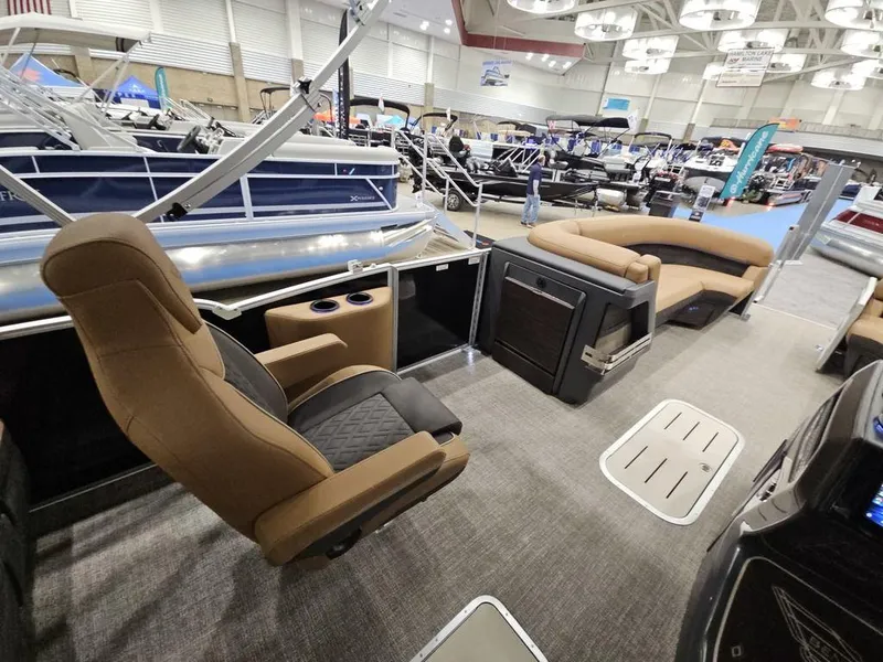 Slide: The Image of 2025 Bennington M Swingback 24 MSB interior at a boat show, featuring luxurious seating. - 10
