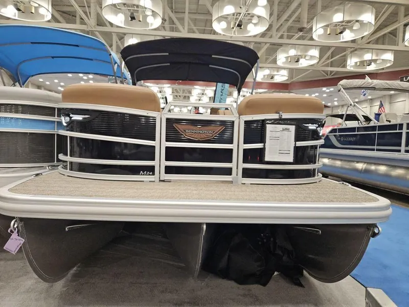 Slide: The Image of 2025 Bennington M Swingback 24 MSB pontoon boat displayed at an indoor boat show. - 11