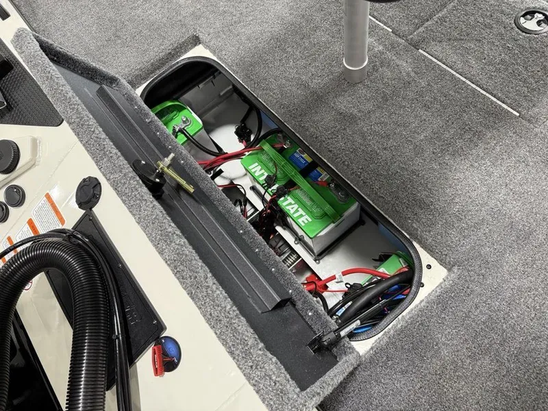 Slide: The Image of Battery compartment of 2025 Tracker Savage 215 boat, featuring green batteries and wiring. - 18