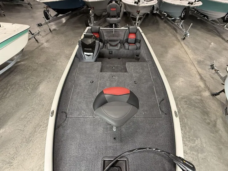 Slide: The Image of 2025 Tracker Savage 215 boat interior with seating and storage, displayed in a showroom. - 19